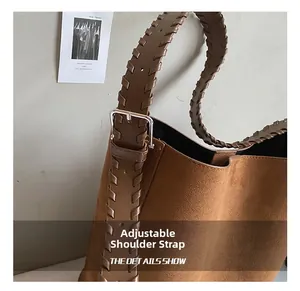 Detail of woven leather strap and silver buckle on brown suede bucket shoulder bag