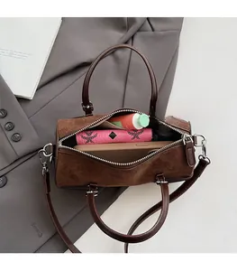 Spacious interior of dark brown cylinder bag showing phone, wallet, and cosmetics