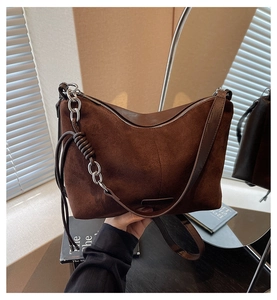 Close-up of deep brown suede tote bag with metallic chain and side tassel detail