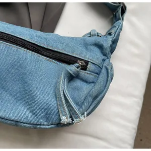Detailaufnahme des schwarzen Reißverschlusses an der hellblauen Denim-Umhängetasche