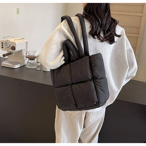 Detail of black quilted down fabric tote bag with soft texture in a modern cafe setting