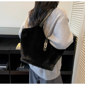 Détail d'un sac seau en fausse fourrure noire avec fine bandoulière en cuir et boucle argentée
