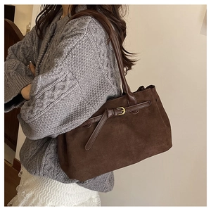 Dettaglio della borsa in pelle scamosciata marrone con fibbia dorata su maglione vintage