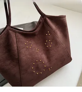 Detail of dark brown faux suede tote bag featuring metallic stud circular pattern