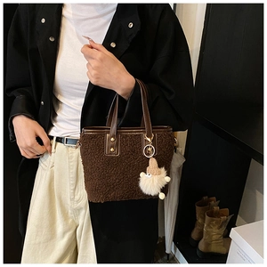 Detail of plush brown bucket bag showing lamb-like faux fur texture and leather handle
