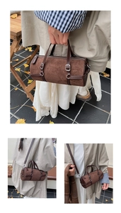 Detail of dark brown suede bowling bag with dual handles and adjustable shoulder strap