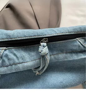 Nahaufnahme des schwarzen Metallreißverschlusses mit blauem Denim-Knoten am Beutel
