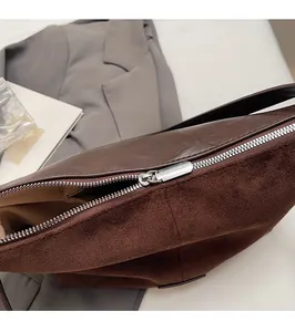 Detail of silver smooth zipper and dark brown suede texture on a vintage crossbody bag