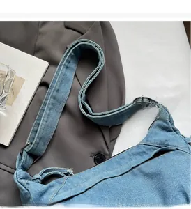 Detail einer hellblauen Denim-Tragetasche mit verstellbarer Metallschnalle und Reißverschluss