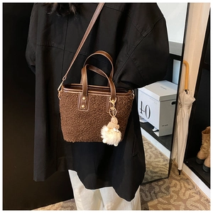 Détail du sac seau en peluche marron avec lanières en cuir et pendentif sur mannequin