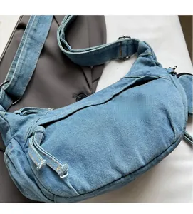 Gros plan sur le sac demi-lune en denim bleu clair montrant texture et surpiqûres