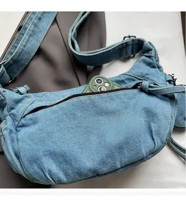 Detailansicht der Reißverschlusstasche der Denim-Umhängetasche mit einem Smartphone