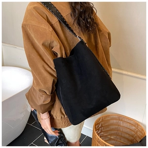 Detail of a black suede bucket bag featuring a thick braided shoulder strap for women