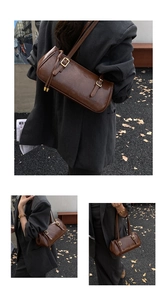 Détail d'un sac cylindre en cuir marron vintage avec fines bretelles et boucles dorées