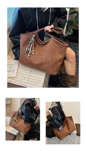 Detail of brown suede tote bag featuring metallic studs and a decorative beaded tassel