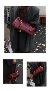 Détail du sac baguette en cuir verni bordeaux avec texture brillante et boucles dorées