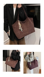 Detail of large brown suede tote bag with gold studs and bohemian tassel charm
