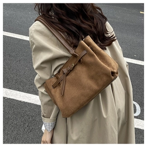Borsa tote in camoscio marrone con fibbia dorata indossata con un trench elegante su strada