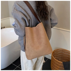 Detailed view of suede bucket bag featuring a brown woven strap and spacious interior