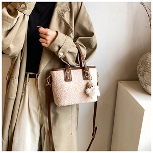 Detail of creamy sherpa bucket bag with brown leather straps shown on a model