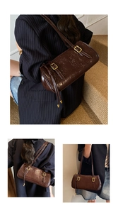 Détail d'un sac sous le bras marron brillant avec boucles dorées sur un costume rayé