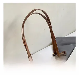 Gros plan sur la texture en cuir ciré marron et boucle dorée du sac à main rétro