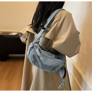 Vue détaillée d'un grand sac bandoulière en denim avec une petite pochette ronde attachée