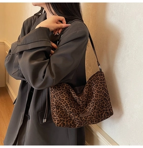 Close-up of leopard print tote bag with metal logo detail worn by a model in a street shot