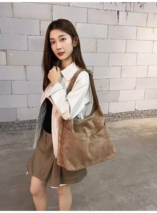 Détail du grand sac hobo en daim marron porté par un mannequin sur une épaule