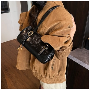 Détail du sac d'épaule en cuir noir brillant avec texture froissée vintage et boucles dorées