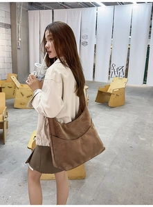 Détail d'un grand sac bandoulière en daim marron avec une poche en forme de demi-lune