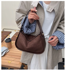 Brown faux suede bowling bag shown in an autumn setting with a minimalist shoulder strap
