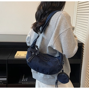 Dettaglio borsa a mezzaluna in denim blu scuro con portamonete rotondo e nappine zip