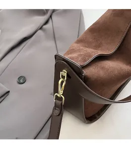 Detail of premium gold hardware and dark brown suede texture on a modern shoulder bag