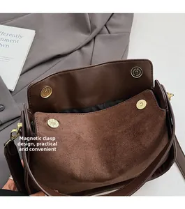 Detail view of the brown suede handbag featuring a secure magnetic clasp closure