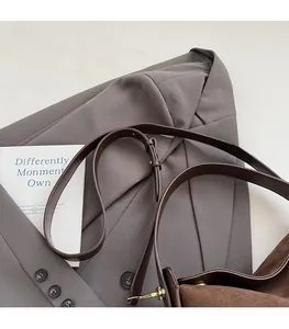 Detail of premium brown leather strap with gold metal buckle on a suede shoulder bag