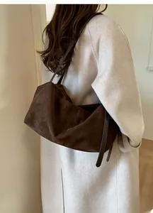 Detail of dark brown suede tote bag featuring adjustable buckle on side and slim shoulder strap