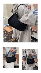 Detailed view of black faux suede half-moon shoulder bag in an autumn outdoor setting