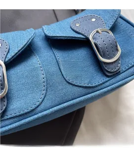 Macro shot of blue denim bag fabric texture with flap pockets and silver buckle details