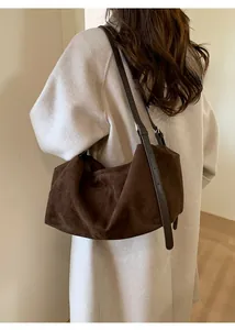 Close-up of brown suede hobo bag shoulder strap details on a light background