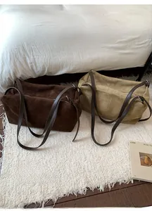 Detail view of large suede tote bags in dark brown and coffee with zipper and long straps