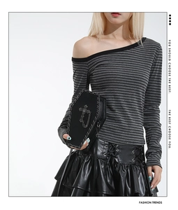 Detail of gothic black coffin bag with metal chain and cross on striped outfit