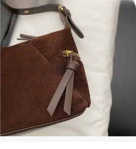 Detail of vintage brown suede bag showing smooth gold metal zipper and leather puller