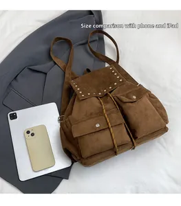 Sac à dos en daim marron présenté à plat avec tablette et téléphone pour comparer la taille
