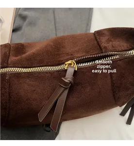 Close-up of smooth gold zipper and soft brown suede texture on vintage underarm bag