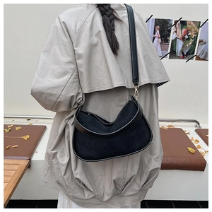 Détail du sac hobo en daim noir avec bordure en cuir et finitions dorées chic