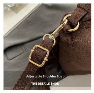 Close-up of adjustable shoulder strap with gold metal buckle on dark brown suede bag