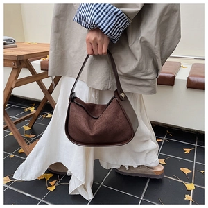 Détail du sac demi-lune en daim marron foncé avec coutures en cuir lisse et boucle en métal