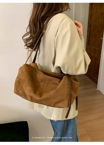 Detail view of a large brown suede tote bag featuring a soft minimalist crescent shape