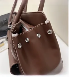 Detailed view of silver snap buttons and stitch craft on a vintage brown tote bag